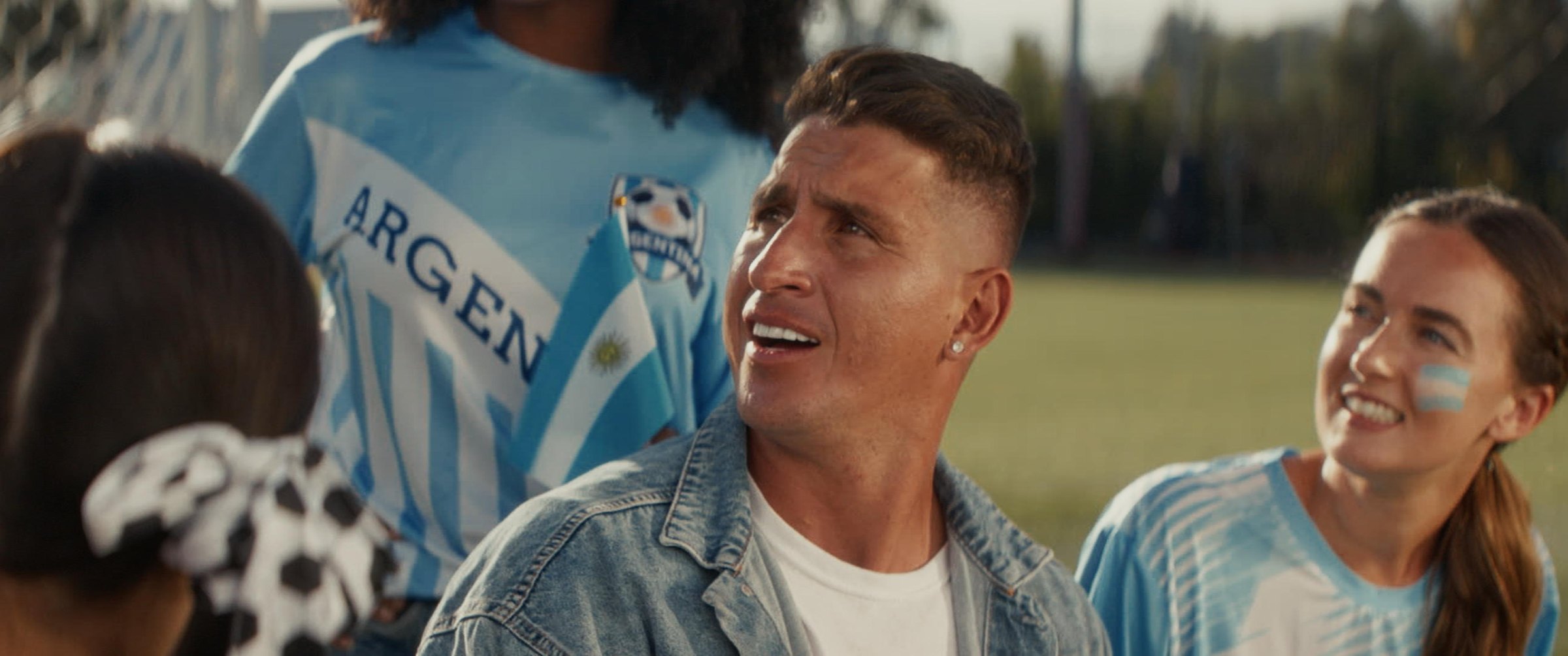 Still from the Argentina football commercial: fans in Argentina jerseys watching in golden light