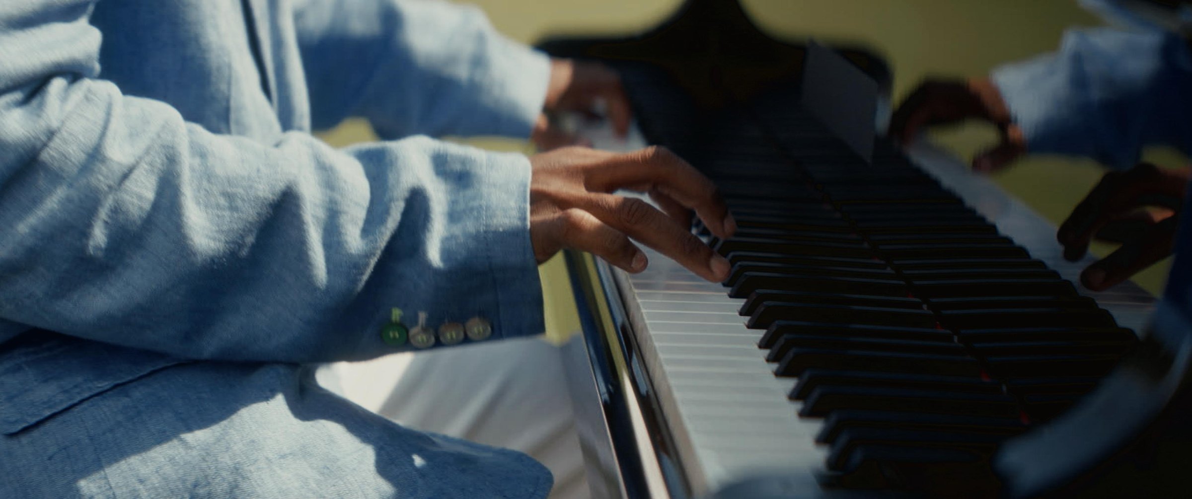 Still from the Argentina football commercial: hands playing a piano in a light blue jacket
