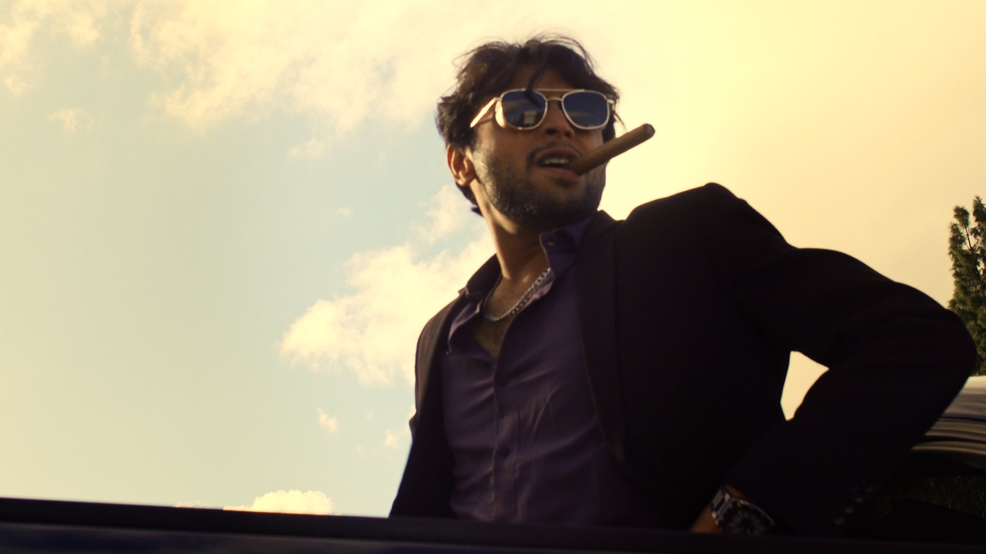 Still from God's Second Best Man: a man in sunglasses with a cigar, low angle against the sky