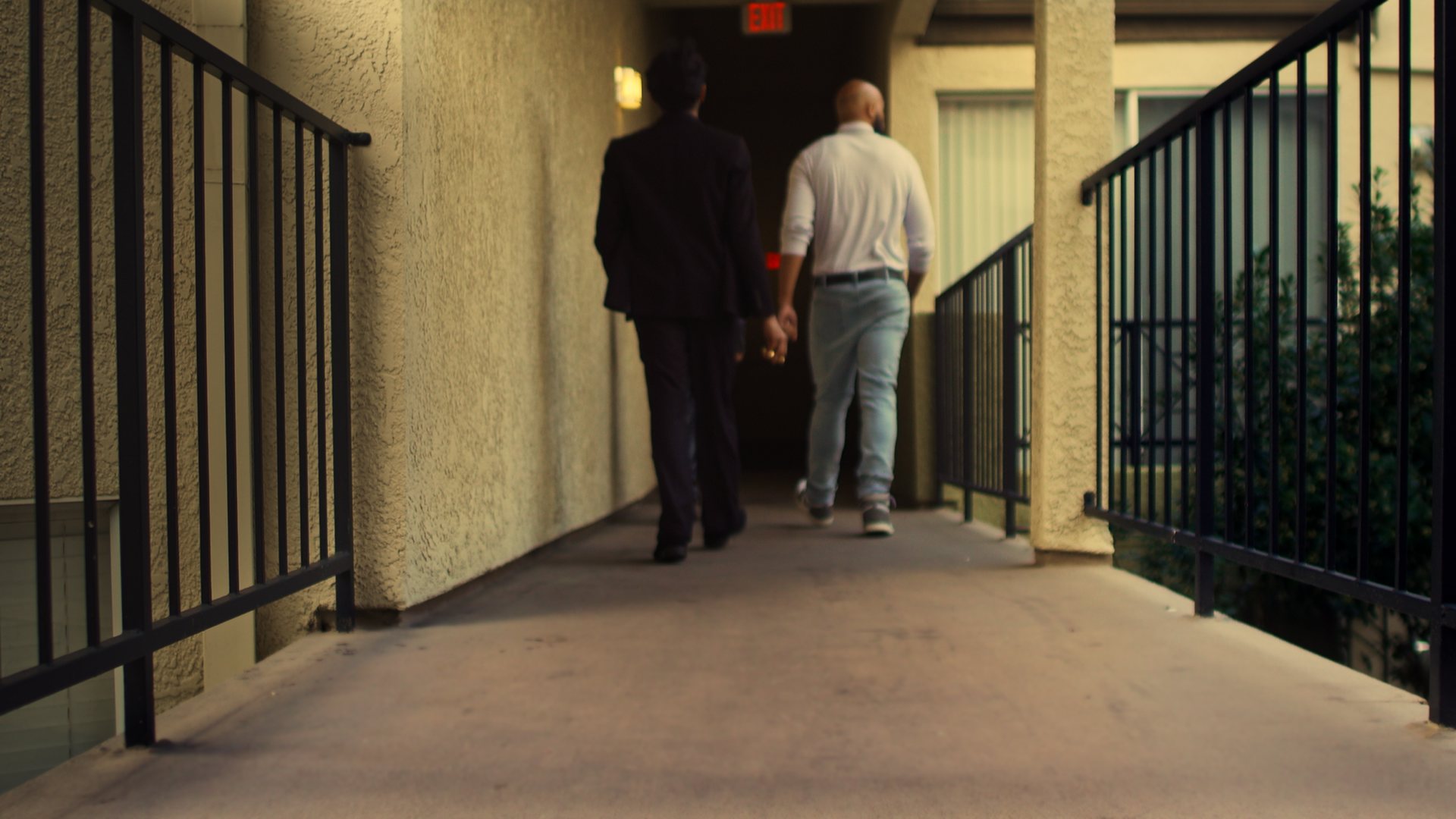 Still from God's Second Best Man: two men walking down an apartment corridor