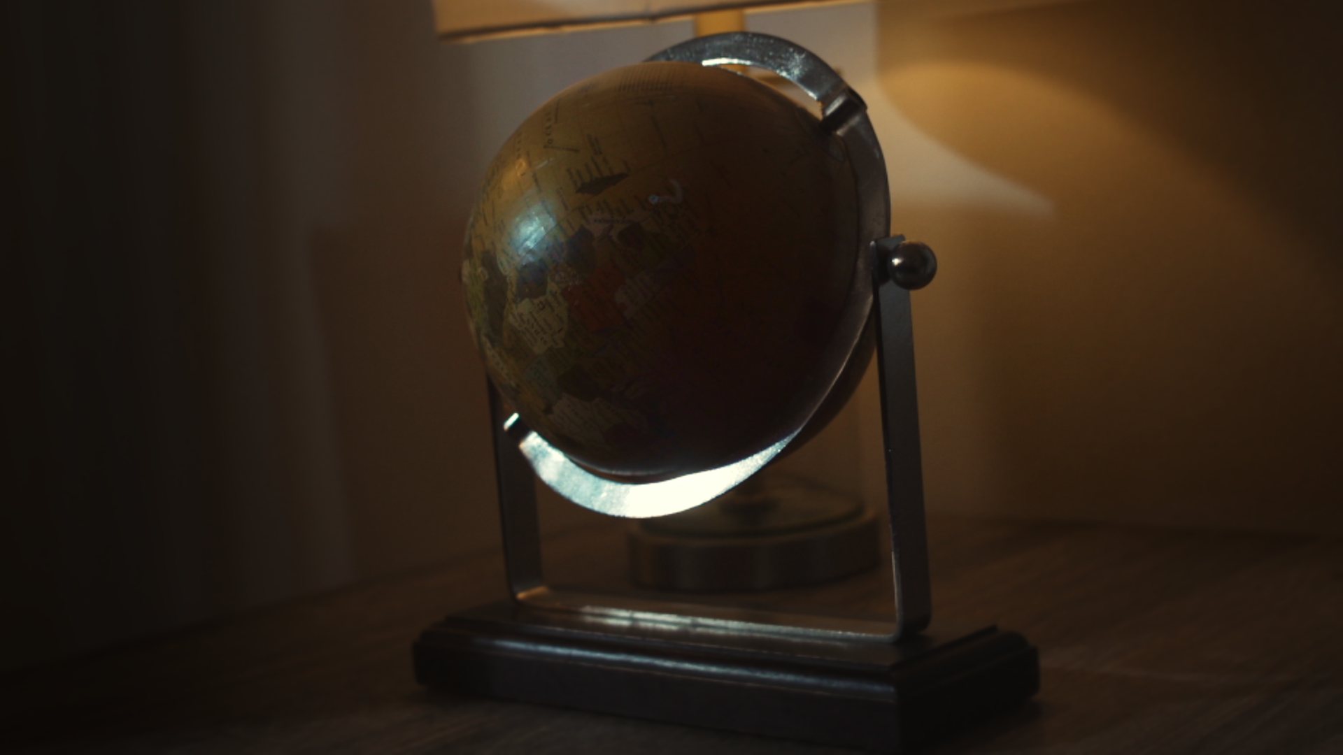 Still from God's Second Best Man: a desk globe in warm lamplight