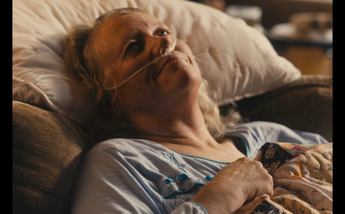 Still from What's Life: an elderly woman in bed looking toward a window