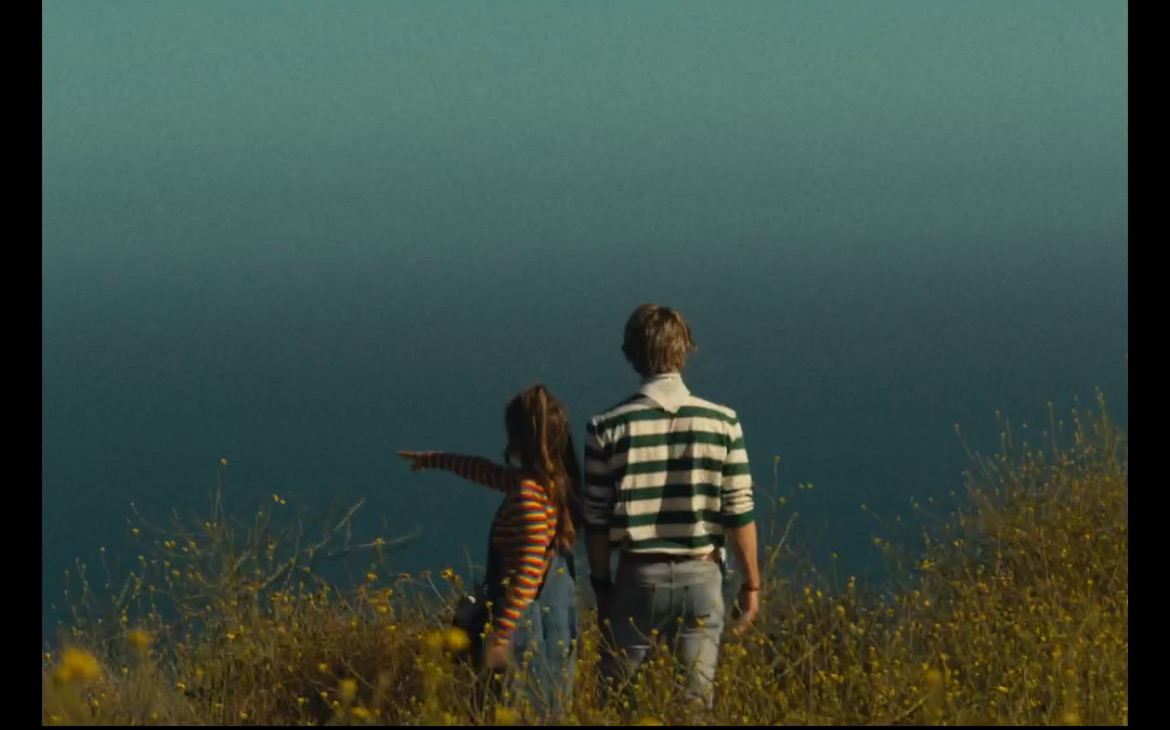 Still from What's Life: a couple standing in tall grass facing the sea